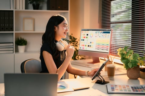 Graphic designer using a digital tablet in a modern workspace filled with colour charts and design tools
